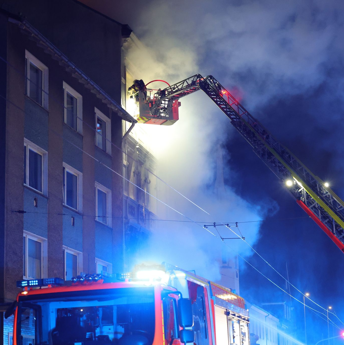 Von einer Drehleiter aus bekämpft ein Feuerwehrmann den Brand in dem Mehrfamilienhaus. - Foto: Gianni Gattus/Blaulicht Solingen/dpa