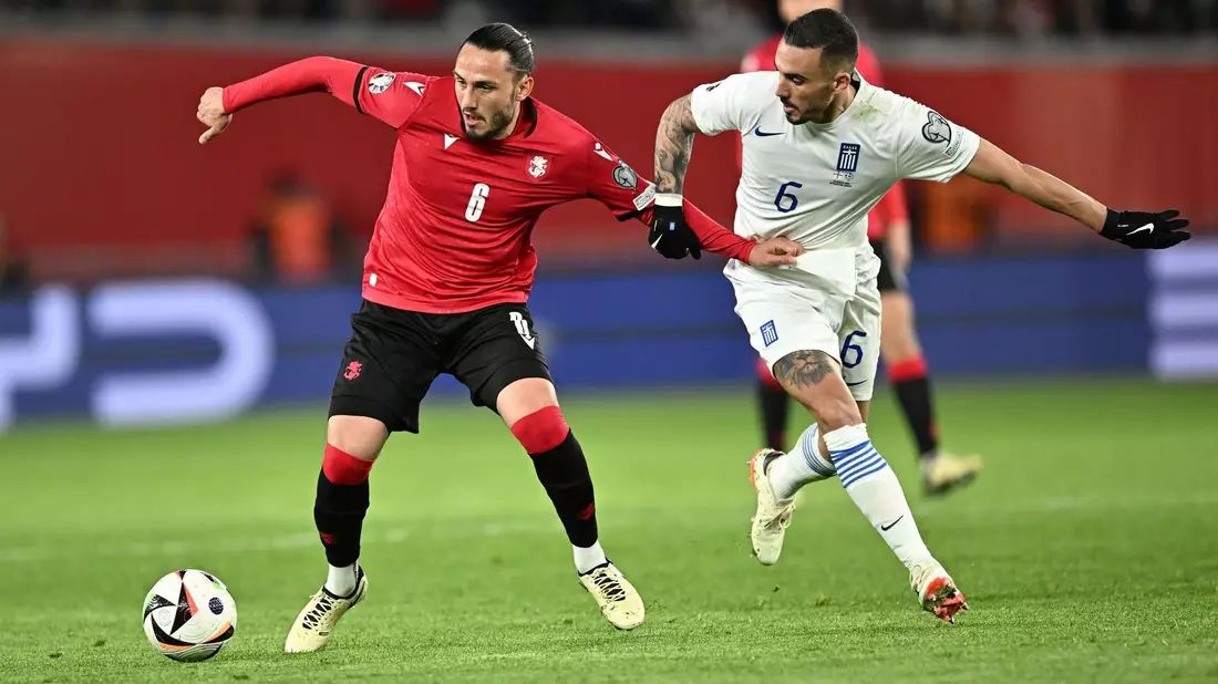 Der Georgier Giorgi Kotschoraschwili (l) behauptet den Ball gegen Dimitris Kourbelis. - Bild: Tamuna Kulumbegashvili/AP/dpa