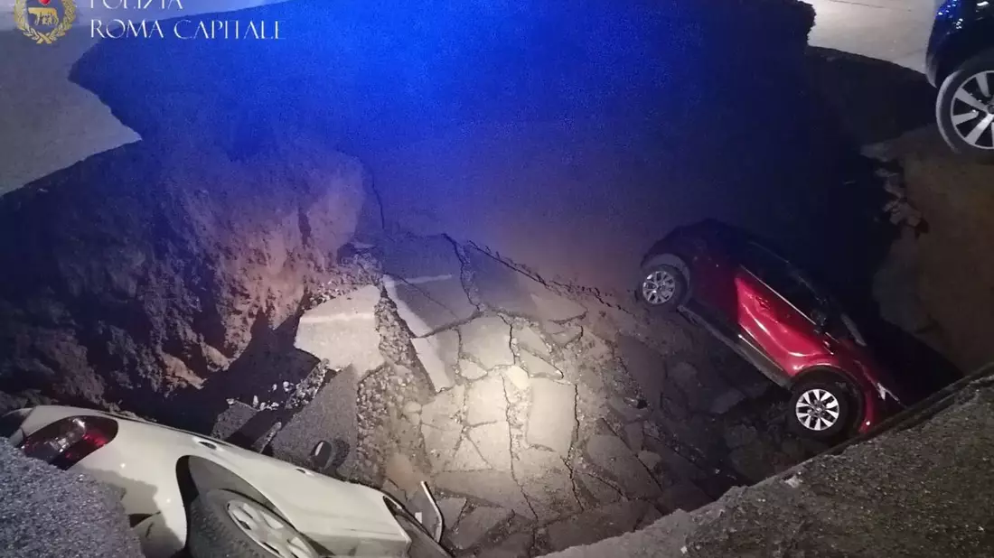 Die zwei geparkten Autos liegen in dem Erdloch. - Bild: Polizia Roma Capitale/dpa