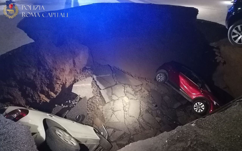 Die zwei geparkten Autos liegen in dem Erdloch. - Foto: Polizia Roma Capitale/dpa