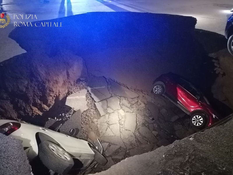 Die zwei geparkten Autos liegen in dem Erdloch. - Foto: Polizia Roma Capitale/dpa