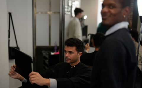 Ein Kunde prüft seine Frisur in einem Friseursalon in Paris (Symbolfoto). Französische Gesetzgeber haben einem Gesetzentwurf, der die Diskriminierung aufgrund von Haarschnitt oder Frisur verbietet, ihre Zustimmung erteilt. - Foto: Thibault Camus/AP/dpa