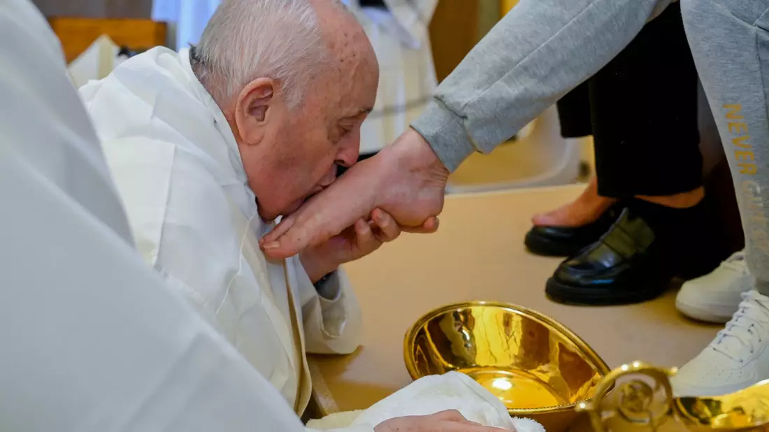 Papst Franziskus küsst den Fuß von einer weiblichen Insassin des Rebibbia-Gefängnisses. - Bild: Vatican Media/AP/dpa