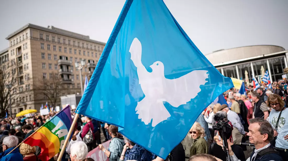 Eine Flagge mit der Friedenstaube ist auf dem traditionellen Ostermarsch in Berlin zu sehen. - Bild: Fabian Sommer/dpa