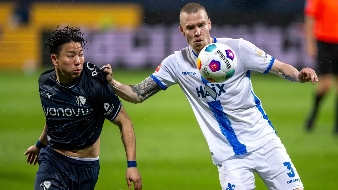 Darmstadts Thomas Isherwood (r) im Zweikampf mit dem Bochumer Takuma Asano. - Bild: David Inderlied/dpa