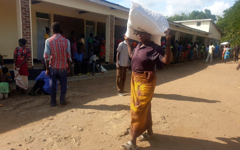 Eine Frau trägt einen Sack mit Maismehl, den sie in einem Verteilungszentrum des Welternährungsprogramms erhalten hat: Im südlichen Afrika wurde der Notstand ausgerufen. - Foto: Kenneth Jali/AP/dpa