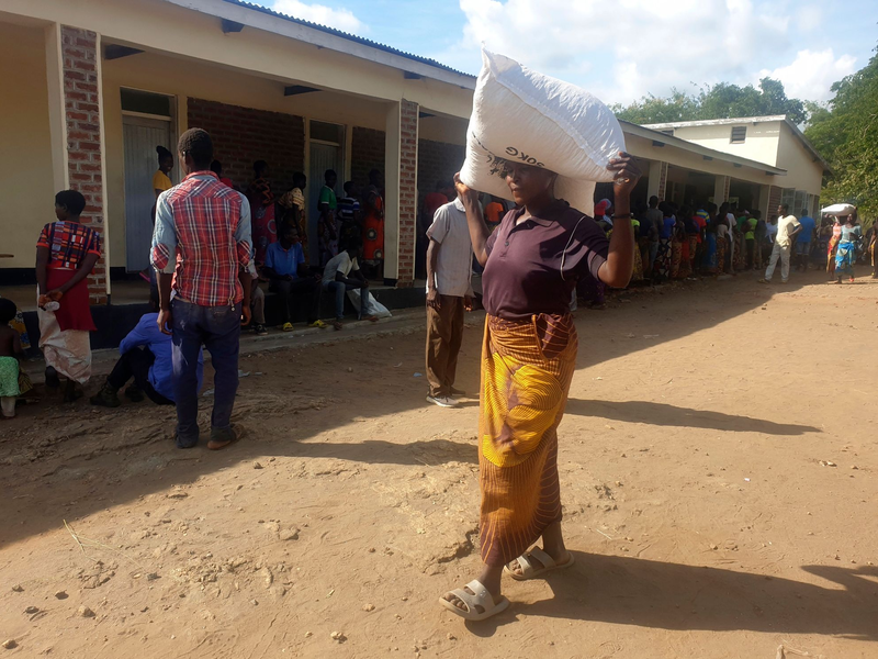 Eine Frau trägt einen Sack mit Maismehl, den sie in einem Verteilungszentrum des Welternährungsprogramms erhalten hat: Im südlichen Afrika wurde der Notstand ausgerufen. - Foto: Kenneth Jali/AP/dpa