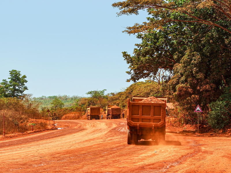 Lastwagen transportieren Bauxit entlang einer Bergbau-Transportstraße. Laut einer Studie werden mehr als ein Drittel der Menschenaffenpopulation in Afrika durch Bergbau gefährdet. - Foto: Claude Frenette/iDiv/dpa