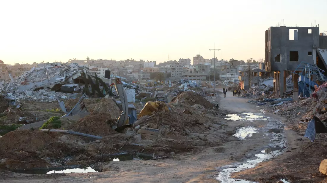Menschen gehen an Trümmern und Ruinen auf einer Straße im Flüchtlingslager Al-Maghazi im Zentrum des Gazastreifens vorbei. - Bild: -/XinHua/dpa