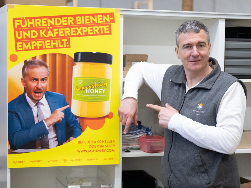 Imker Rico Heinzig neben einem Plakat mit dem Foto des Moderators Jan Böhmermann. - Foto: Sebastian Kahnert/dpa