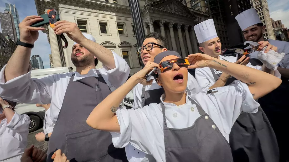 Angestellte eines Restaurants in Manhattan machen eine Pause, um die Sonnenfinsternis zu betrachten. - Bild: John Minchillo/AP/dpa