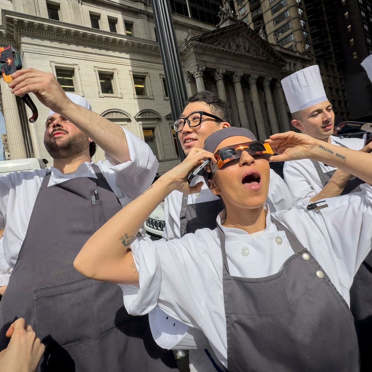 Angestellte eines Restaurants in Manhattan machen eine Pause, um die Sonnenfinsternis zu betrachten. - Foto: John Minchillo/AP/dpa