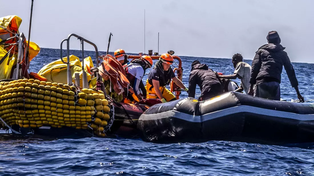 Das Rettungspersonal von SOS Mediteranee hilft Migranten bei der Evakuierung eines Schlauchbootes. Überlebende berichteten, dass etwa 50 Menschen während der Fahrt ums Leben gekommen waren. - Bild: Johanna de Tessieres/SOS Mediteranee/AP/dpa