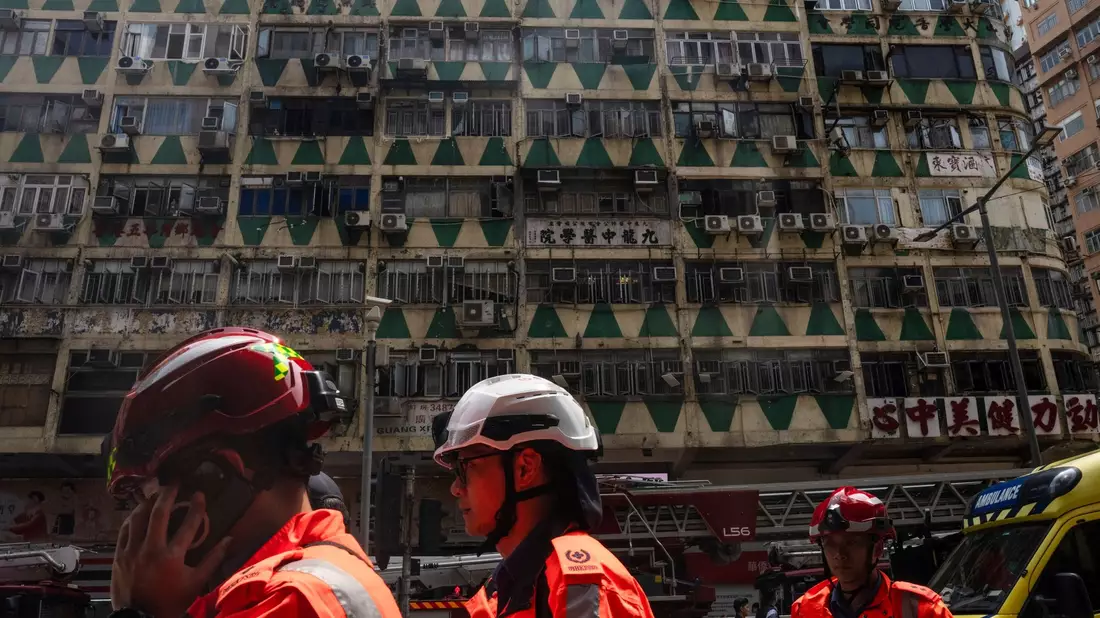 Im Hintergrund ist das ausgebrannte Hochhaus in Hongkong zu sehen - bei der Feuerwehr waren zahlreiche Hilferufe eingegangen. - Bild: Louise Delmotte/AP