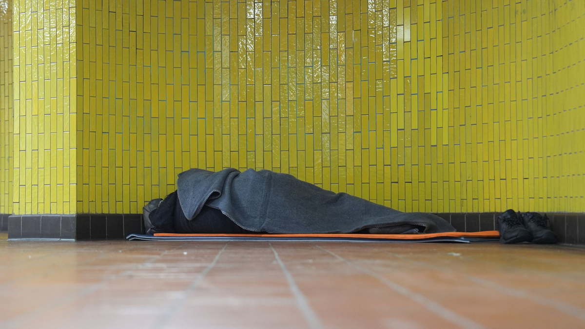 Ein Obdachloser liegt in seinem Schlafsack in einer U-Bahnstation in der Hamburger Innenstadt. 17,7 Millionen Menschen waren 2023 in Deutschland von Armut oder Ausgrenzung bedroht. - Foto: Marcus Brandt/dpa