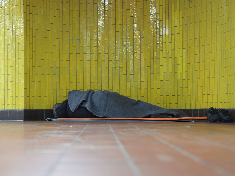 Ein Obdachloser liegt in seinem Schlafsack in einer U-Bahnstation in der Hamburger Innenstadt. 17,7 Millionen Menschen waren 2023 in Deutschland von Armut oder Ausgrenzung bedroht. - Foto: Marcus Brandt/dpa