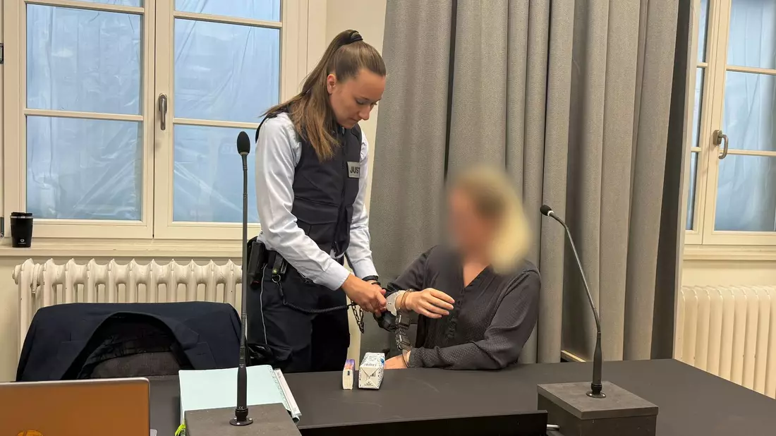 Eine Justizmitarbeiterin nimmt der Angeklagten beim Prozessauftakt vor dem Landgericht Ravensburg die Handschellen ab. - Bild: Aleksandra Bakmaz/dpa
