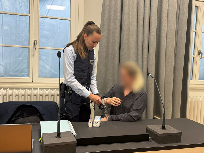 Eine Justizmitarbeiterin nimmt der Angeklagten beim Prozessauftakt vor dem Landgericht Ravensburg die Handschellen ab. - Foto: Aleksandra Bakmaz/dpa