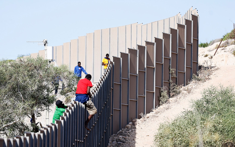 Migranten klettern über einen Zaun auf der Insel Lampedusa. - Foto: Cecilia Fabiano/LaPresse via ZUMA Press/dpa