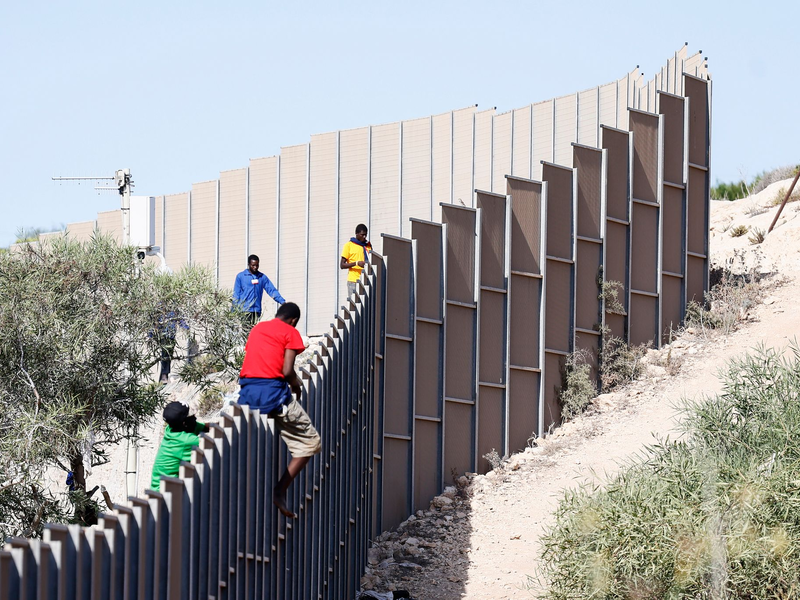 Migranten klettern über einen Zaun auf der Insel Lampedusa. - Foto: Cecilia Fabiano/LaPresse via ZUMA Press/dpa