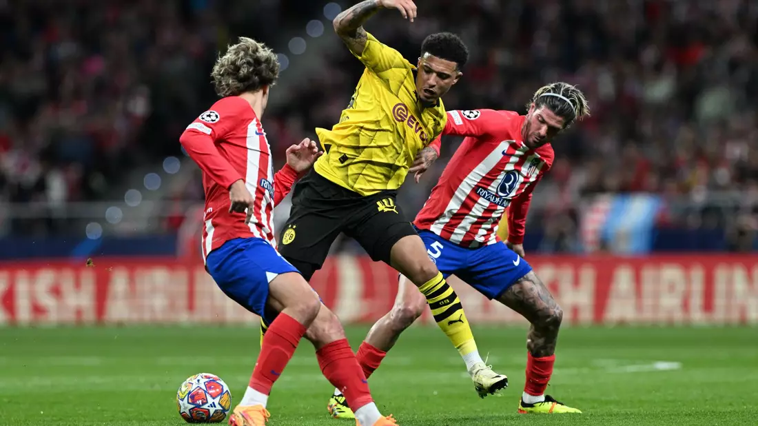 Jadon Sancho (M.) wird gleich von zwei Atlético-Profis angegriffen. - Bild: Federico Gambarini/dpa