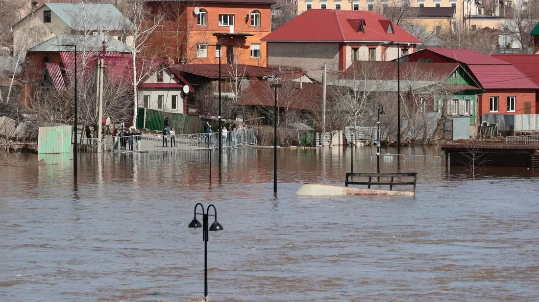 Anwohner stehen an einer Absperrung und beobachten ein überschwemmtes Gebiet im russischen Orenburg. - Bild: Uncredited/AP/dpa