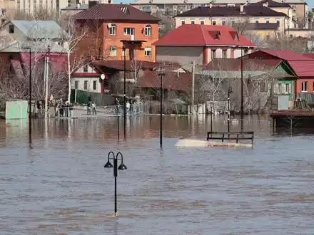 Anwohner stehen an einer Absperrung und beobachten ein überschwemmtes Gebiet im russischen Orenburg. - Foto: Uncredited/AP/dpa
