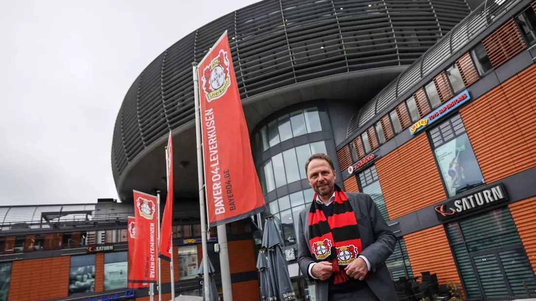 Uwe Richrath, Oberbürgermeister von Leverkusen, steht mit einem Fanschal vor dem Rathaus. - Bild: Oliver Berg/dpa