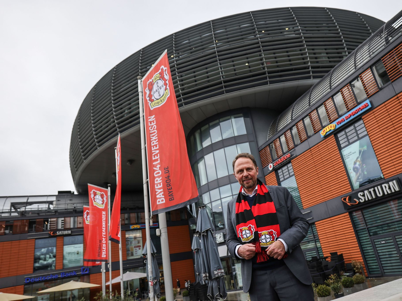 Uwe Richrath, Oberbürgermeister von Leverkusen, steht mit einem Fanschal vor dem Rathaus. - Foto: Oliver Berg/dpa