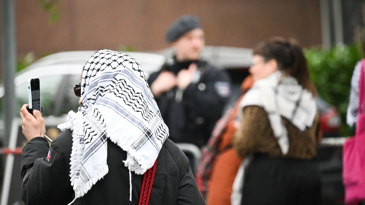 Teilnehmer des «Palästina-Kongresses» und Polizisten stehen vor der Veranstaltungshalle in Berlin-Tempelhof. - Foto: Sebastian Christoph Gollnow/dpa