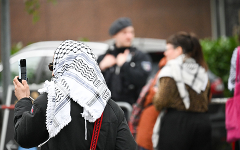 Teilnehmer des «Palästina-Kongresses» und Polizisten stehen vor der Veranstaltungshalle in Berlin-Tempelhof. - Foto: Sebastian Christoph Gollnow/dpa