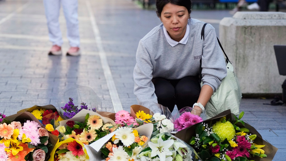 Eine Frau bringt Blumen zu einer improvisierten Gedenkstätte an der Bondi Junction. - Foto: Rick Rycroft/AP/dpa