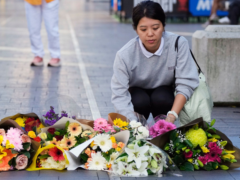 Eine Frau bringt Blumen zu einer improvisierten Gedenkstätte an der Bondi Junction. - Foto: Rick Rycroft/AP/dpa