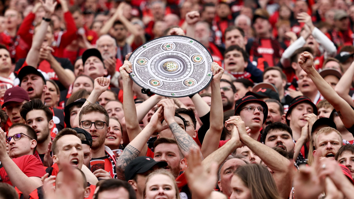 Fußball: Ein Leverkusener Fan hält während des Spiels eine Nachbildung der Meisterschale in den Händen. Bayer Leverkusen gewinnt die Deutsche Meisterschaft. - Foto: Rolf Vennenbernd/dpa