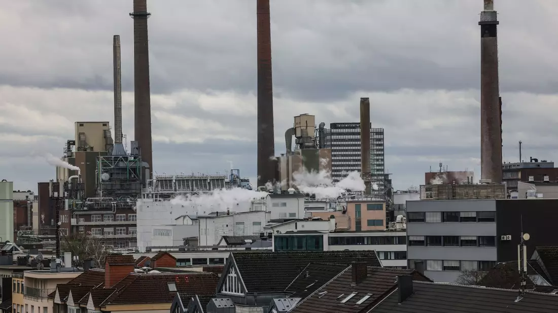 Prägend: Hinter Wohnhäusern sind die Anlagen des Werkes von Bayer in Leverkusen zu sehen. - Bild: Oliver Berg/dpa
