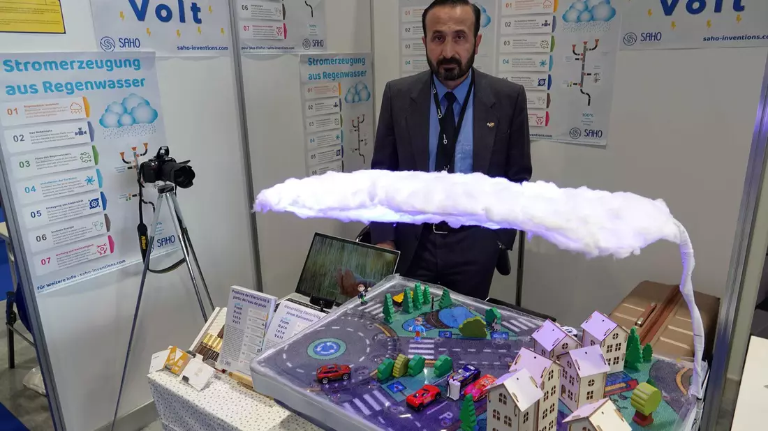 Khaled Al-Saho steht hinter seinem Modell, das die Produktion von Energie aus Regenwasser erklärt. - Bild: Christiane Oelrich/dpa