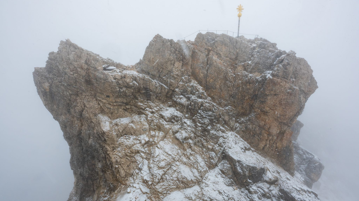 Nebelwolken umhüllen bei Schneetreiben auf der Zugspitze die Aussichtsplattform mit dem Gipfelkreuz (Archivbild). Aus 
mehreren Bergsteigergruppen wurden Notrufe abgesetzt, nachdem sie aufgrund von Witterung und Neuschnee auf etwa 2500 Metern Höhe nicht mehr weiterkamen. - Foto: Peter Kneffel/dpa
