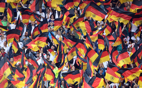 Fans schwenken Deutschlandfahnen auf der Tribüne. - Foto: Uli Deck/dpa