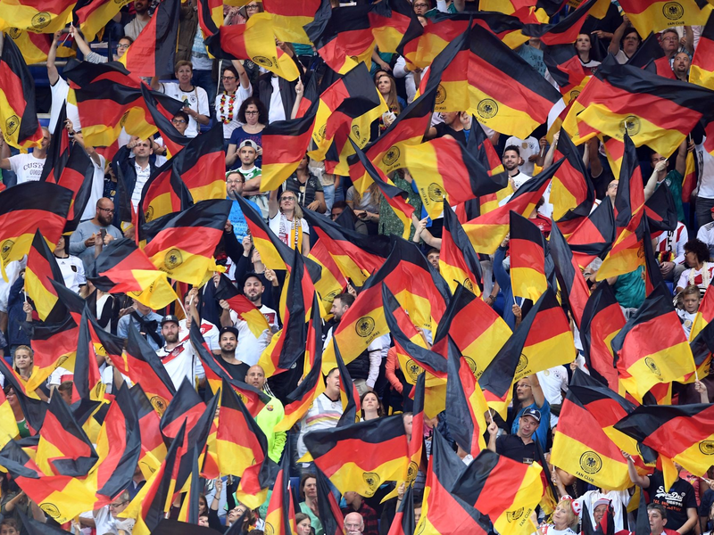 Fans schwenken Deutschlandfahnen auf der Tribüne. - Foto: Uli Deck/dpa