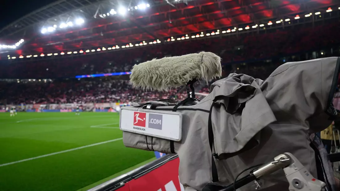 Eine TV-Kamera steht am Spielfeldrand. - Bild: Robert Michael/dpa