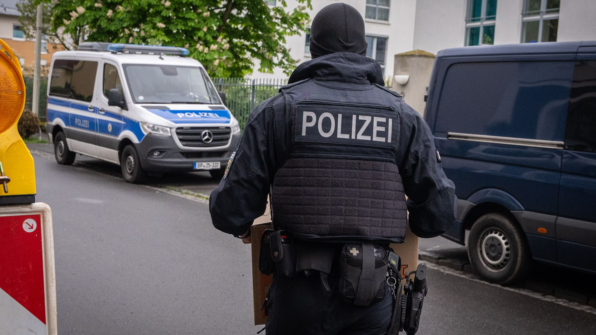 Ein Polizist trägt bei einem Einsatz in Bonn einen Karton mit beschlagnahmtem Material aus einem Gebäude. - Foto: Benjamin Westhoff/dpa