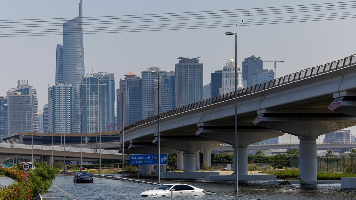 Ein Mann trägt ein Kind durch das von starkem Regen verursachte Hochwasser in Dubai. - Foto: Christopher Pike/AP/dpa