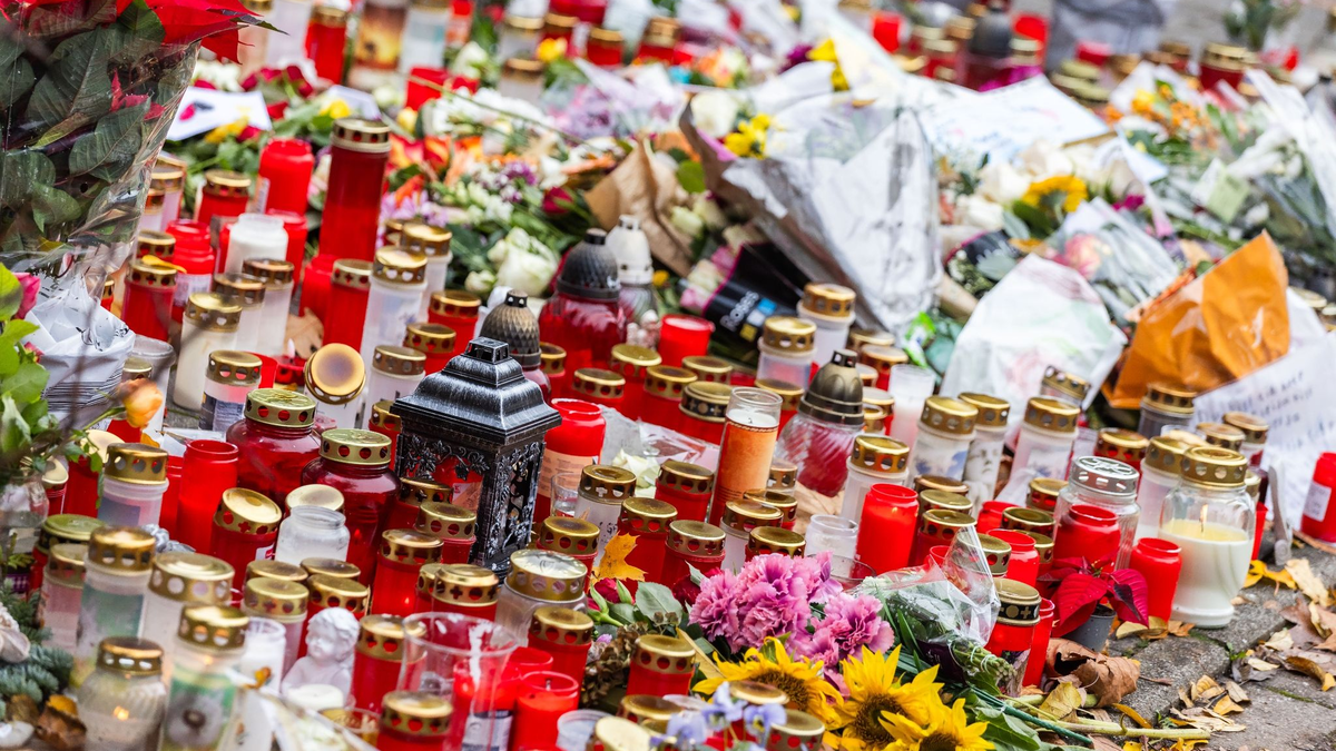 Kerzen und Blumen liegen vor dem Eingang der Waldbachschule. - Foto: Philipp von Ditfurth/dpa