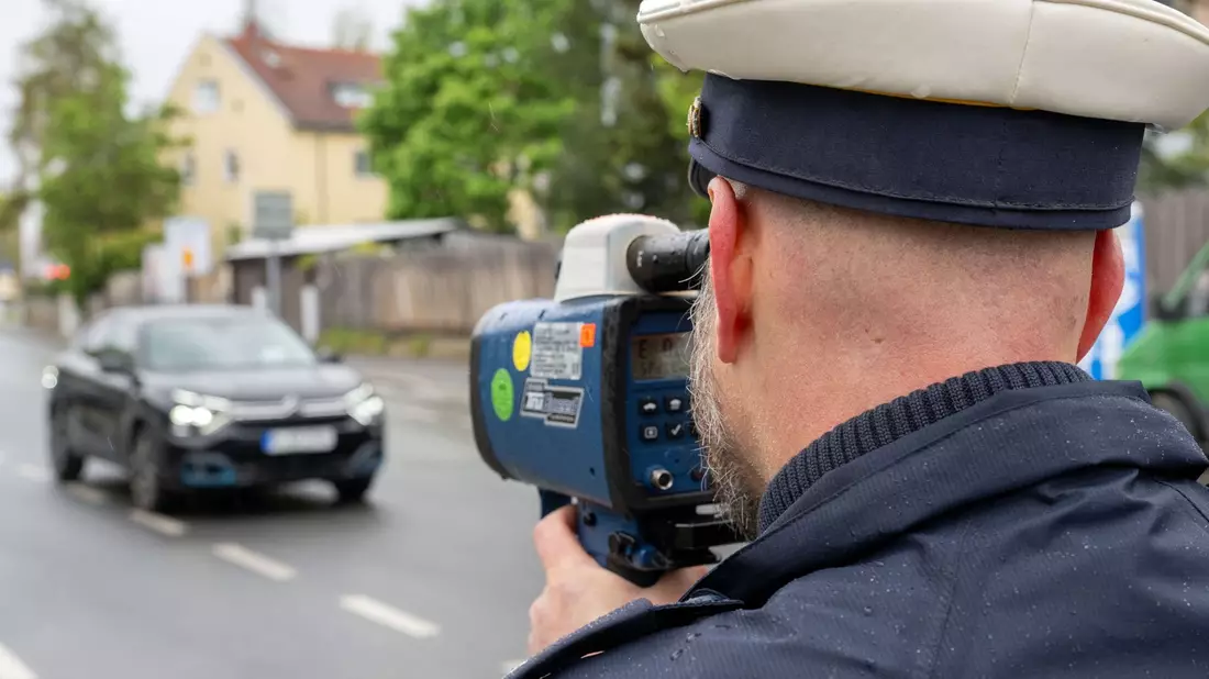 Ein Polizeibeamter nimmt in Nürnberg einen Verkehrsteilnehmer mit einem Messgerät ins Visier. - Bild: Pia Bayer/dpa
