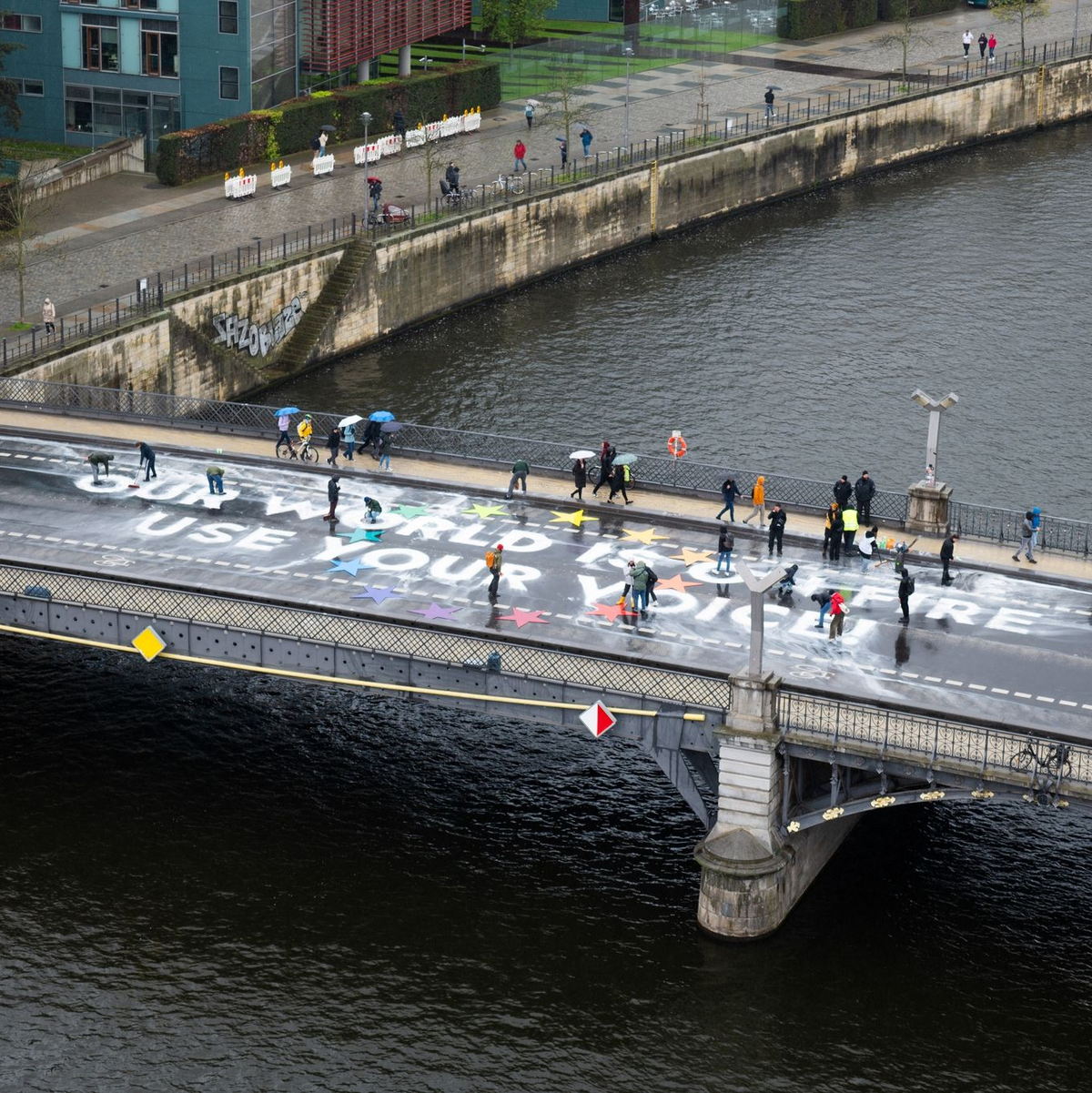 Klimaaktivisten der Bewegung Fridays for Future malen auf der Marschallbrücke in Berlin den Schriftzug «Our world is on fire - use your voice!». - Foto: Christophe Gateau/dpa