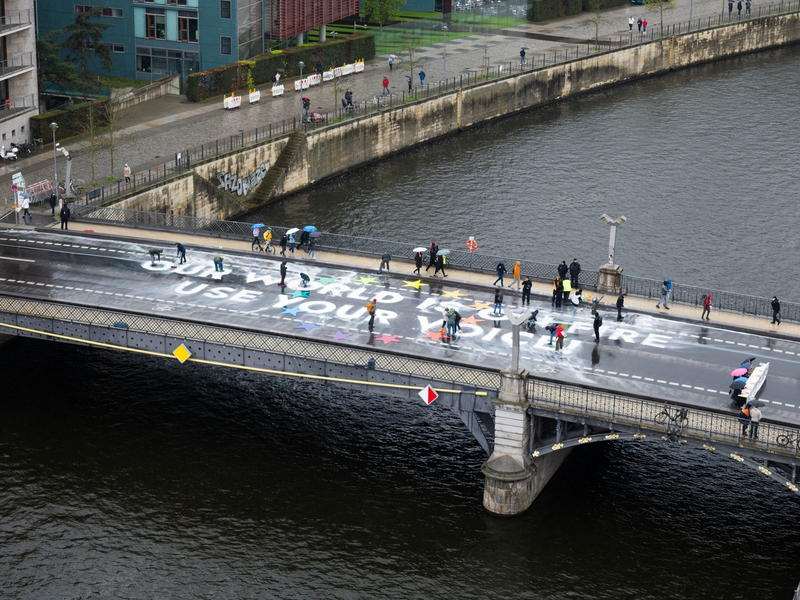 Klimaaktivisten der Bewegung Fridays for Future malen auf der Marschallbrücke in Berlin den Schriftzug «Our world is on fire - use your voice!». - Foto: Christophe Gateau/dpa