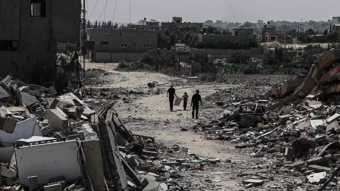 Palästinenser gehen neben zerstörten Wohngebäuden im Lager Nuseirat im zentralen Gazastreifen entlang. - Bild: Omar Ashtawy/APA Images via ZUMA Press Wire/dpa