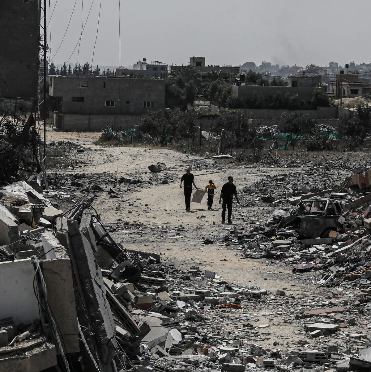 Palästinenser gehen neben zerstörten Wohngebäuden im Lager Nuseirat im zentralen Gazastreifen entlang. - Foto: Omar Ashtawy/APA Images via ZUMA Press Wire/dpa