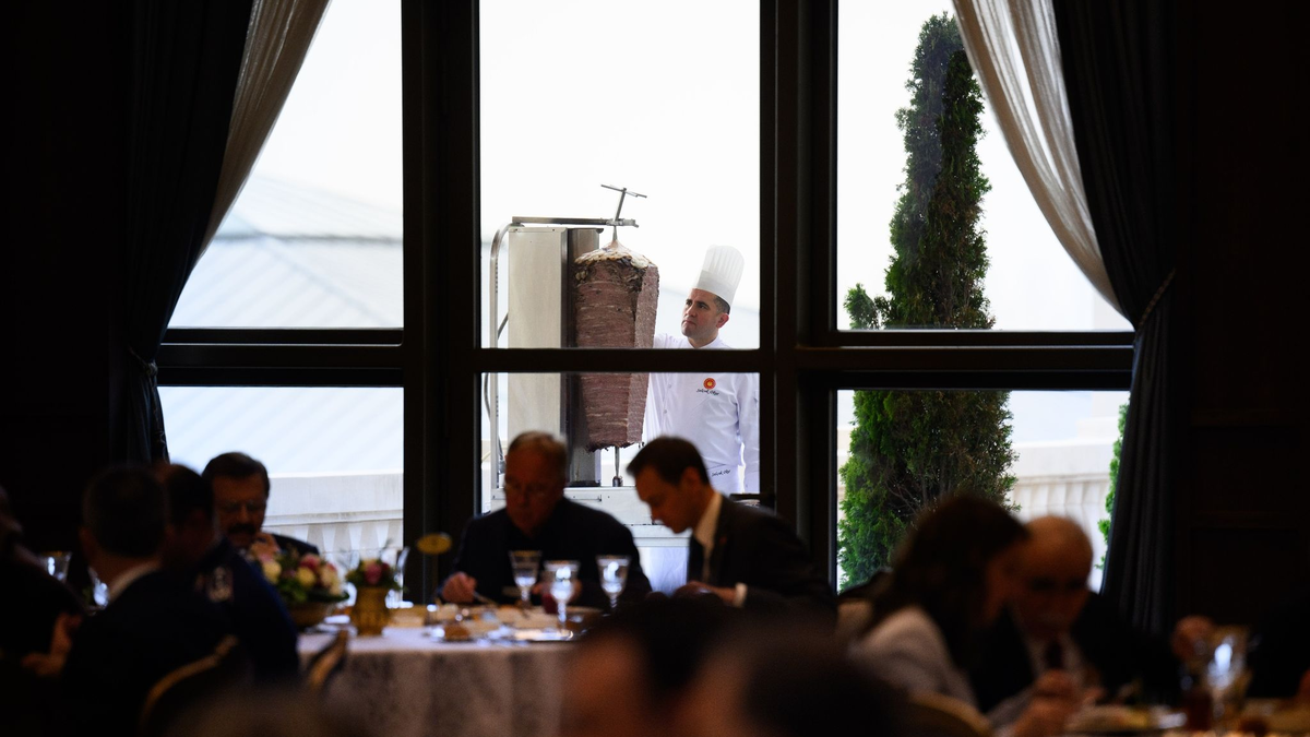 Ein Koch bereitet auf einer Terrasse des Präsidialpalasts Dönerfleisch vom Spieß zu. - Foto: Bernd von Jutrczenka/dpa