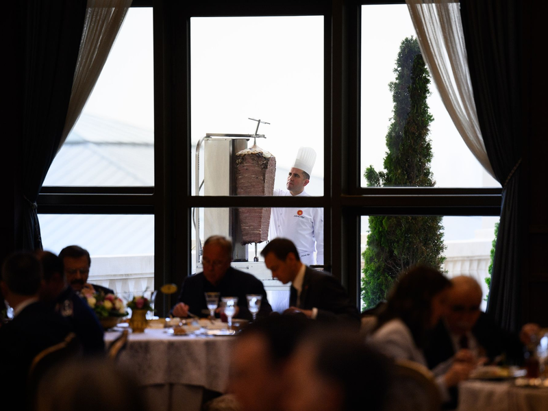Ein Koch bereitet auf einer Terrasse des Präsidialpalasts Dönerfleisch vom Spieß zu. - Foto: Bernd von Jutrczenka/dpa